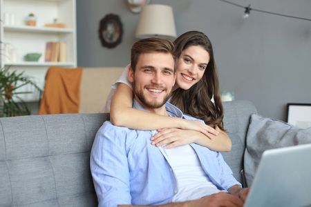 Young couple doing some online shopping at home, using a laptop on the sofaの写真素材