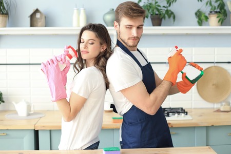 Young happy couple is having fun while doing cleaning at home