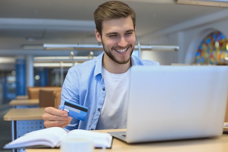 Portrait of young man sitting at his desk in the officeの写真素材