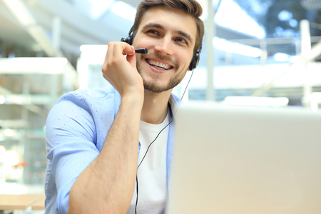 Happy young male customer support executive working in officeの写真素材