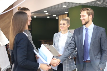 Business partners handshaking over business objects on workplaceの写真素材