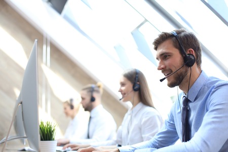 Portrait of call center worker accompanied by his team. Smiling customer support operator at work