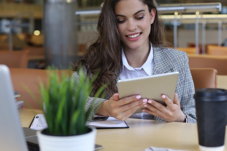 Young smiling businesswoman in office working on digital tabletの写真素材