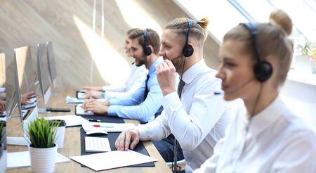 Portrait of call center worker accompanied by his team. Smiling customer support operator at workの写真素材