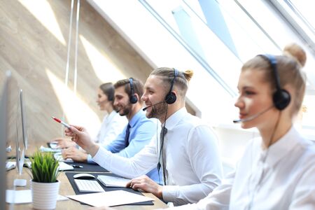 Portrait of call center worker accompanied by his team. Smiling customer support operator at workの写真素材