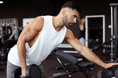 Fit and muscular man trains with dumbbellsの写真素材