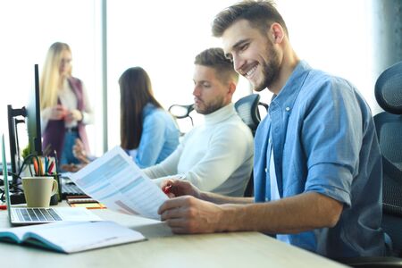 Young modern colleagues in smart casual wear working together while spending time in the creative...