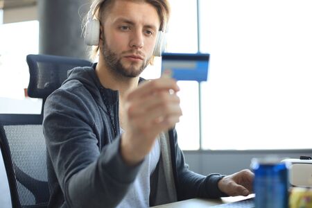 portrait of a young man holds and using credit card for game money top up