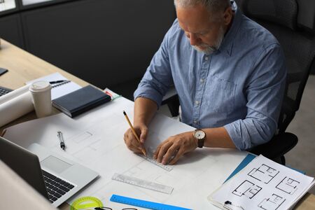 Good looking mature architect drawing something while working in the office