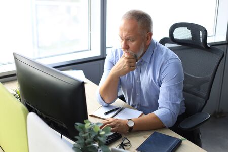 Focused mature businessman deep in thought while sitting at a table in modern office