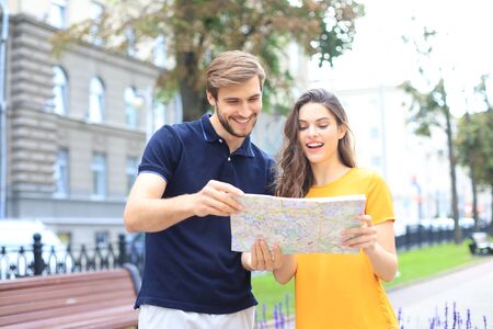 Image of young cute loving couple walking outdoors while holding map.の写真素材