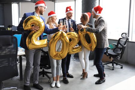 Business people are celebrating holiday in modern office drinking champagne and having fun in coworking. Merry Christmas and Happy New Year 2020.の写真素材