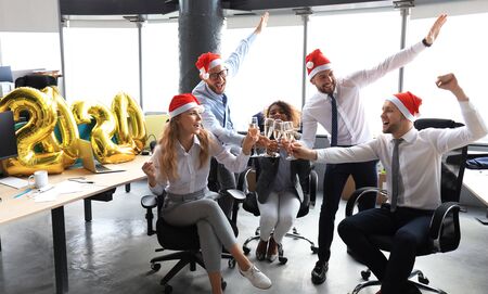 Business people are celebrating holiday in modern office drinking champagne and having fun in coworking. Merry Christmas and Happy New Year 2020.の写真素材