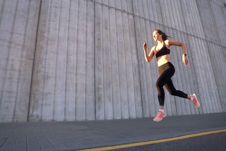 Young attractive woman with perfect slim body running outdoors. Fitness and running concept
