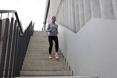 Runner athlete running on stairs. Woman fitness is jogging oudoors