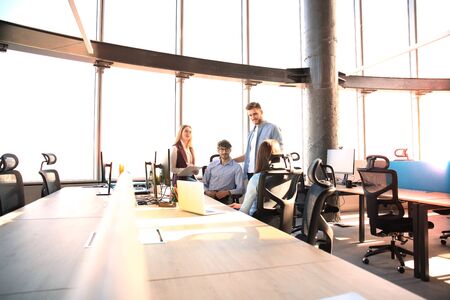 Young colleagues in smart casual wear working while spending time in the office.