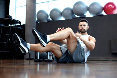 Sporty man stretching and warm-up doing special exercises for muscles before work his body out.