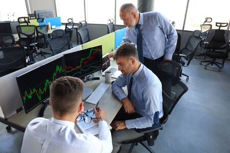 Group of modern business men in formalwear analyzing stock market data while working in the officeの写真素材