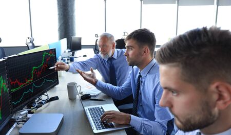 Group of modern business men in formalwear analyzing stock market data while working in the officeの写真素材