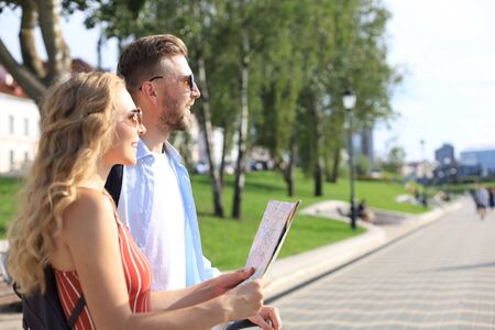 Lovely couple on vacation are looking at map for direction.