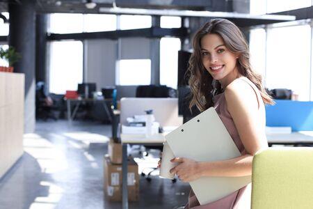 Attractive business woman looking at camera and smiling while standing in the officeの写真素材