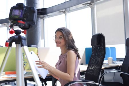 Beautiful young woman talking and smiling while making new video for her blogの写真素材