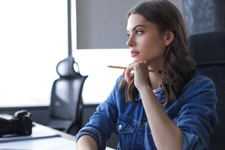 Concentrated young woman writing something down while working in the officeの写真素材
