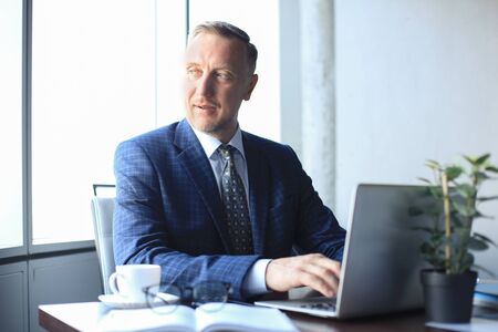 Elegant mature businessman analyzing data while working in office