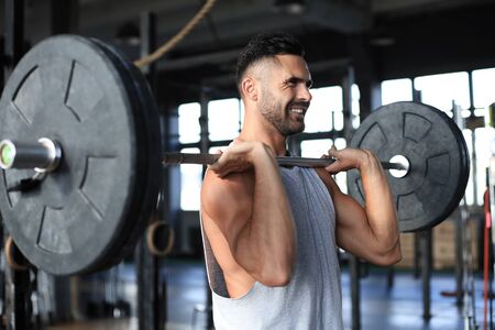 Muscular man working out in gym doing exercises with barbell at bicepsの写真素材