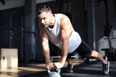 Fit and muscular man focused on lifting a dumbbell during an exercise class in a gym