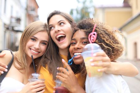 Three trendy cool hipster girls, friends drink cocktail in urban city backgroundの写真素材