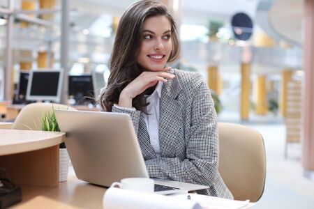 Portrait of a young brunette business woman using laptop at officeの写真素材
