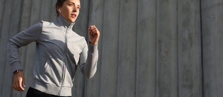 Young attractive sporty fitness woman running while exercising outdoors at sunset or sunrise in...