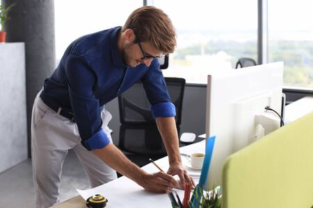 Good looking young business man drawing something while working in the office