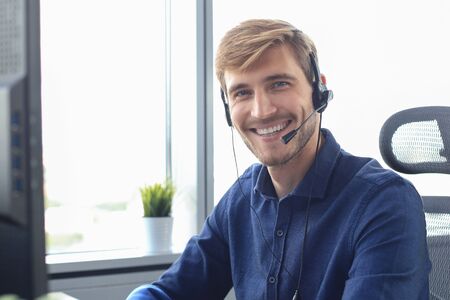 Smiling friendly handsome young male call centre operator.