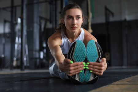 Young sporty woman stretching at the gymの写真素材