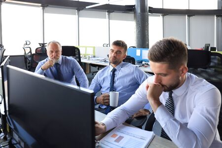 Group of young business men in formalwear working using computers while sitting in the officeの写真素材