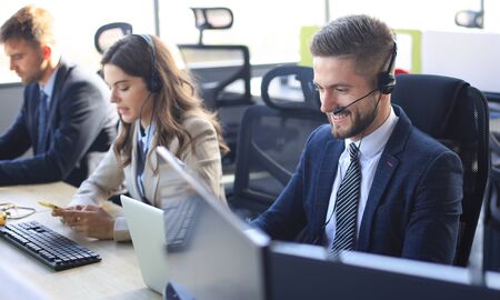 Portrait of call center worker accompanied by his team. Smiling customer support operator at workの写真素材