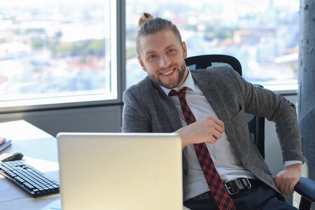 Young modern business man working using laptop while sitting in the office