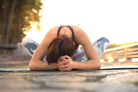 Young pretty woman doing yoga exercises in the park