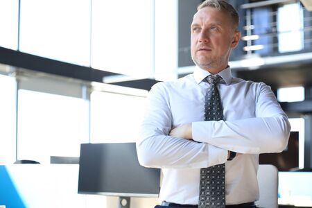 Confident pensive mature business man in modern office