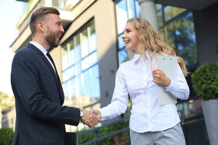 Image of collegues discussing documents and shaking hands near officeの写真素材