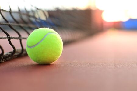 Bright greenish yellow tennis ball on clay courtの写真素材