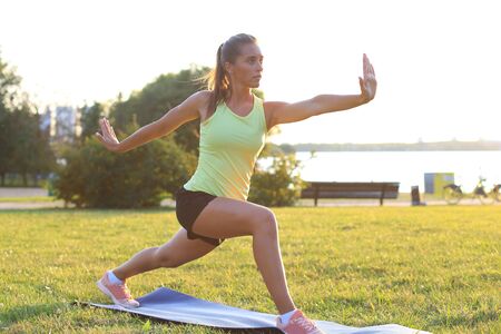 Beautiful young woman in sports clothing stretching while standing outdoors