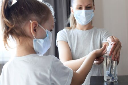 Mother and little daughter washing hand with alcohol sanitizer, prevent the virus and bacterias of...