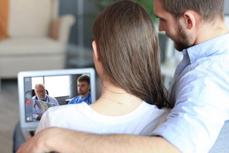 Young couple doing video conference with doctors on laptop. Coronavirus