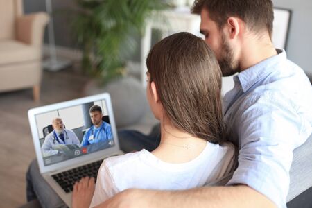 Young couple doing video conference with doctors on laptop. Coronavirusの写真素材