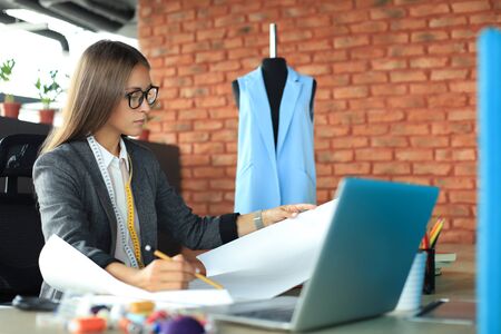 Beautiful young designer working on sketches while sitting in her studioの写真素材