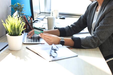Woman holding credit card on laptop for online shopping concept