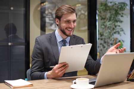 Smiling young business man having video call in office